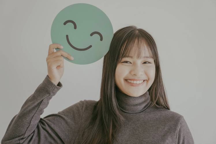 happy-young-asian-woman-holding-smile-emoji-face-2024-10-18-04-56-50-utc